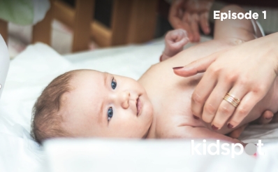 Baby in crib in nappy with mums hands holding them